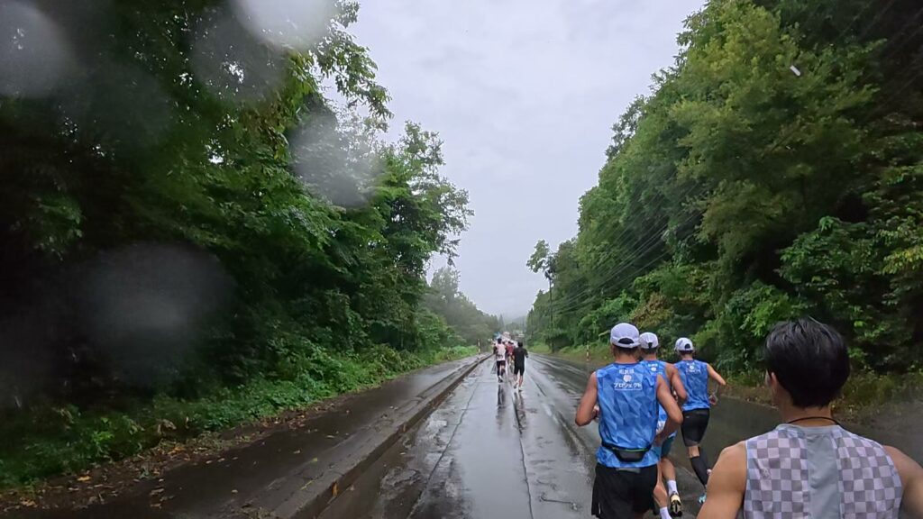 木々に囲まれた道を走るランナーの集団(2.6km付近)
