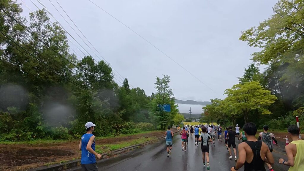 雨の中、スタートしたばかりのランナーの集団（田沢湖マラソン）