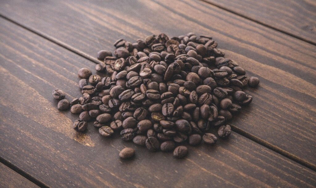木のテーブルに広がる焙煎されたコーヒー豆
